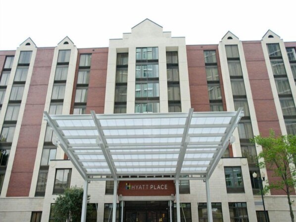 Ein mehrstöckiges Hotel mit moderner Fassade, das einen markanten Eingangsbereich mit einer Glasüberdachung und einem Schild mit der Aufschrift "Hyatt Place" zeigt.
