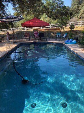 A swimming pool with a red canopy, lounge chairs, and a fenced area. - Private Loft above the barn on horse ranch (Pilot Hill)
