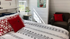 Une chambre à coucher avec un lit, une chaise, une table de chevet et une fenêtre.