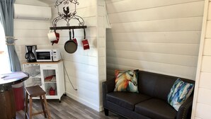 Un salon chaleureux avec un canapé en cuir marron, un tapis coloré et un porte-ustensiles fixé au mur.