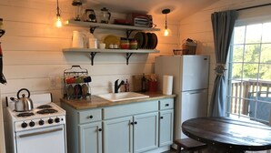 Une cuisine de taille réduite, équipée d’une cuisinière, d’un évier et d’une table en bois.