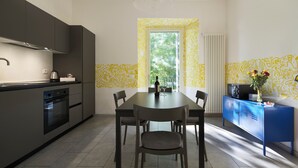 A modern kitchen with a dining area, featuring a large window, a built-in microwave, and a blue cabinet. - House of Arts apartments ♠ (Montelupo Fiorentino)
