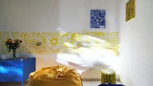 A room with a patterned wall, a blue cabinet, a yellow bean bag, and a small wooden stool. - House of Arts apartments ♠ (Montelupo Fiorentino)