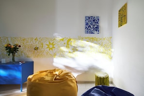 A room with a patterned wall, a blue cabinet, a yellow bean bag, and a small wooden stool. - House of Arts apartments ♠ (Montelupo Fiorentino)