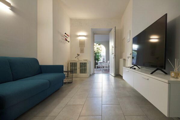 A living room with a sofa, a TV, a cabinet, and a door leading to another room.