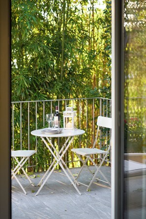 Un balcon avec une table dressée pour deux personnes, une bouteille de vin et une bougie.