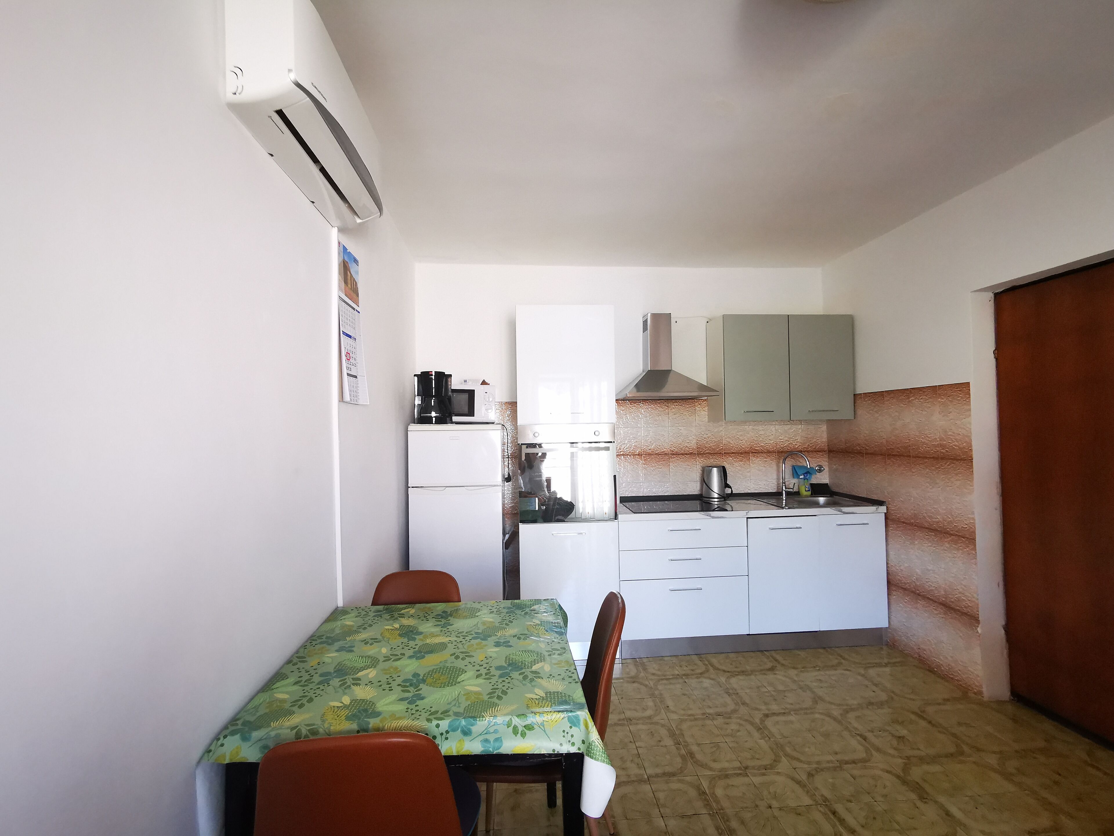 A compact kitchen with white cabinets, a coffee maker, and a microwave.