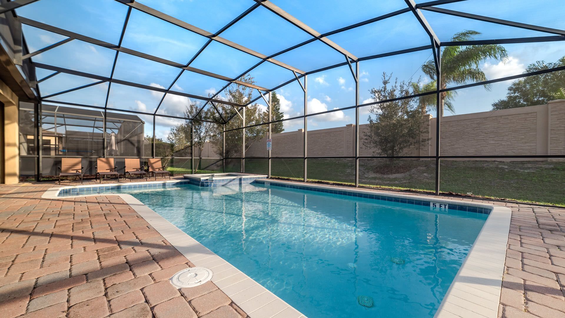 A covered swimming pool with a brick patio and outdoor furniture.