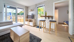 Ein modernes Wohnzimmer mit einer Couch, einem Couchtisch, einem Fernseher und Barhocker.