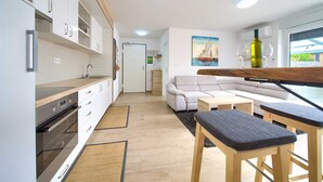 Eine moderne Küche mit weißen Schränken, einem eingebauten Ofen und einem Essbereich mit Holztisch und Stühlen.