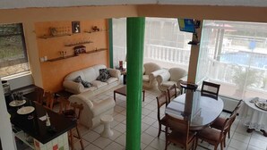 Ein Wohnzimmer mit Essbereich, einer Couch, einem Couchtisch und einem an der Wand befestigten Fernseher.