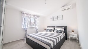 A bedroom with a bed, curtains, a bedside table, and wall art. - Modern Villa Future**** with an outdoor heated pool in a quiet village on Krk (Klimno)