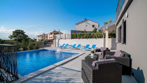 A swimming pool with blue lounge chairs and a wicker sofa. - Modern Villa Future**** with an outdoor heated pool in a quiet village on Krk (Klimno)