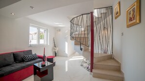 A modern living room with a red sofa, a black coffee table, and a staircase with a metal railing. - Modern Villa Future**** with an outdoor heated pool in a quiet village on Krk (Klimno)