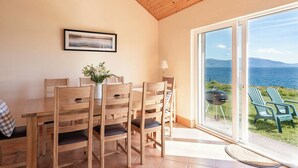 Comedor con muebles de madera, vista al mar y un cuadro en la pared.