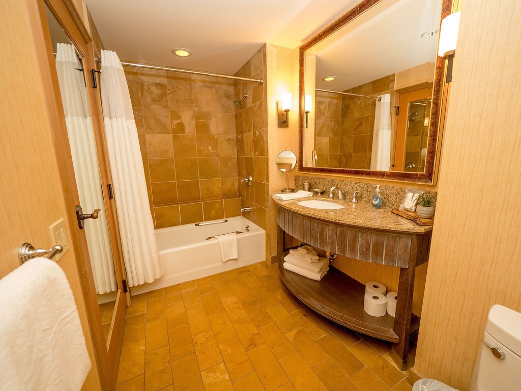 Un baño con bañera, lavamanos, espejo e inodoro.