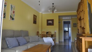 Een woonkamer met een bank, salontafel en een eethoek met stoelen en een tafel.