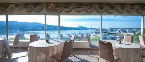 A conference room with a panoramic view of a harbor and mountains.
