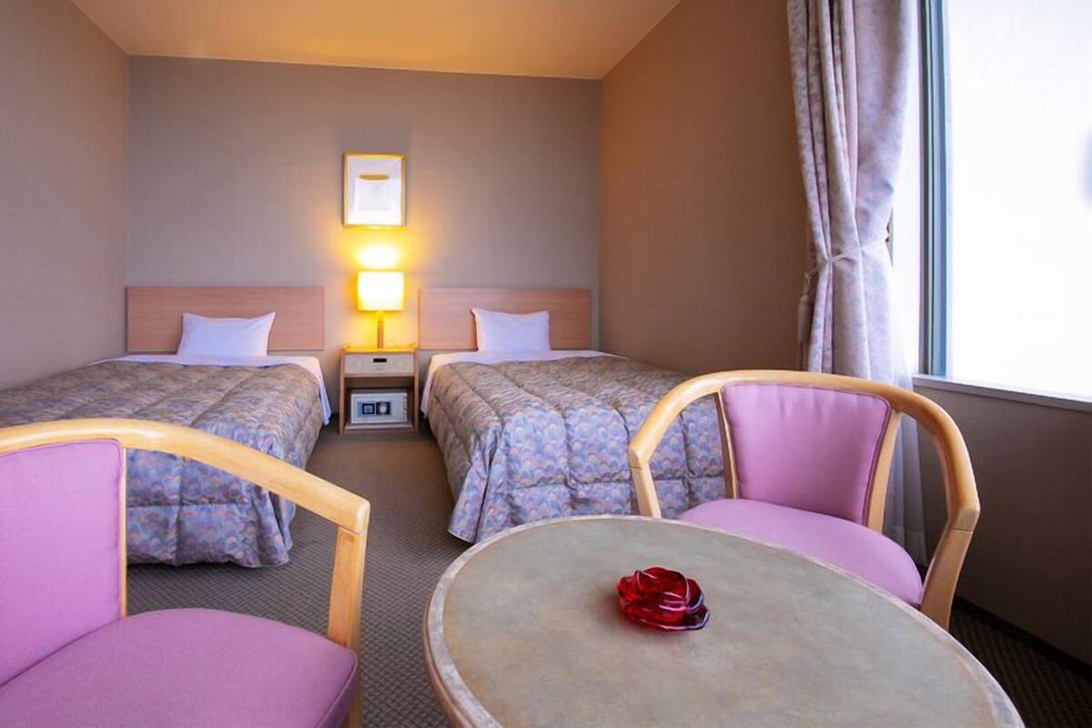 Une chambre d’hôtel avec deux lits, une petite table et deux chaises.