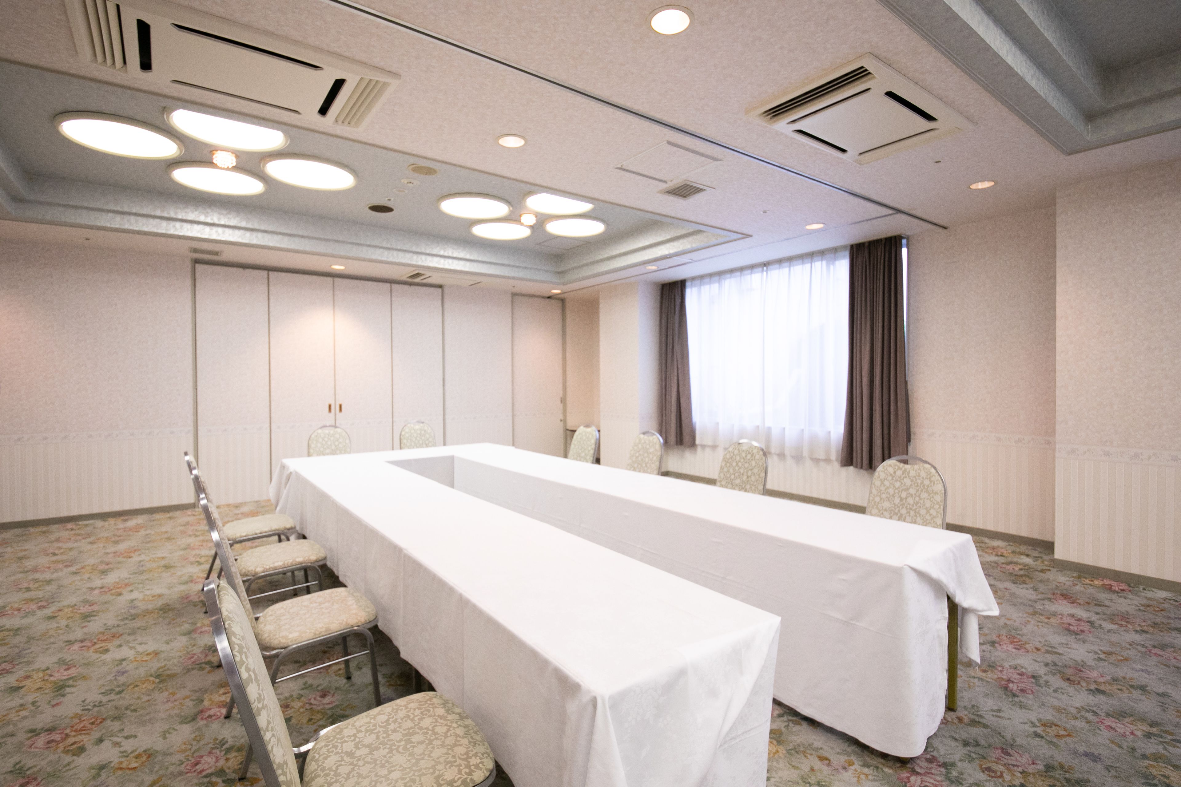 A conference room with a long table, chairs, and a carpeted floor.