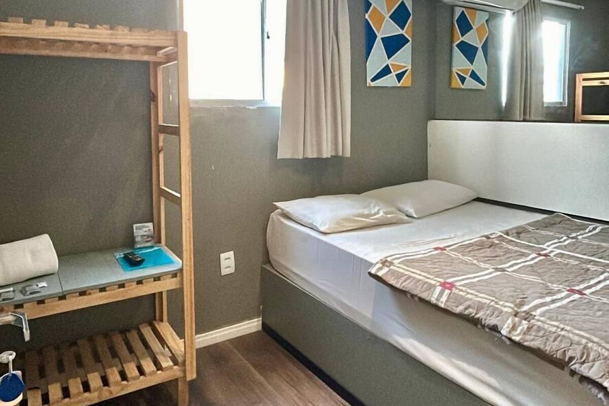A compact room with a bunk bed, a small desk with a chair, and a window with curtains.