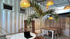 Uma sala de jantar com uma mesa redonda, cadeiras de vime e luminárias de vime pendentes.