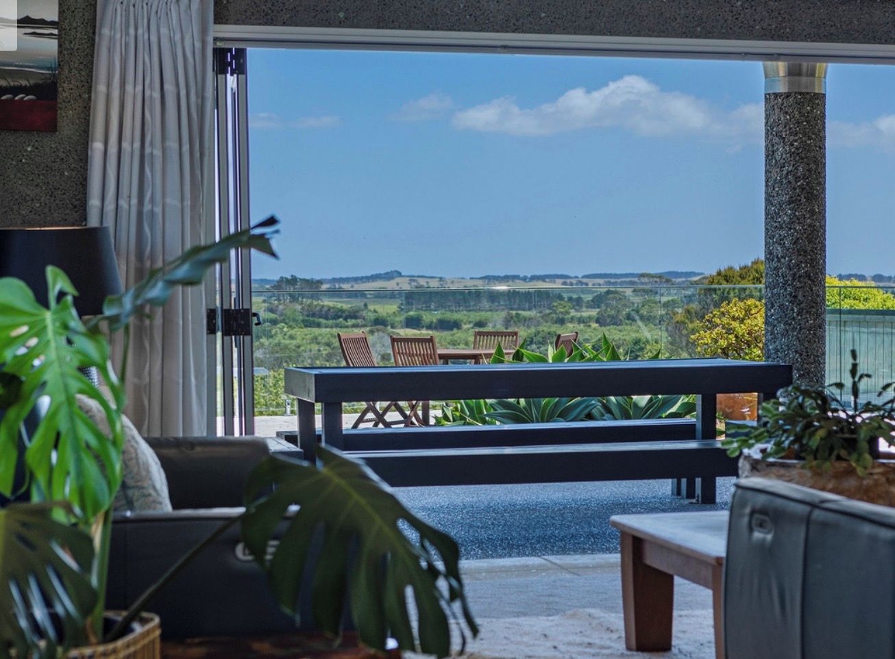 Un salon moderne avec une grande fenêtre, un canapé, une table basse et une vue sur un paysage.