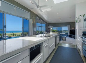 Una cocina moderna con una isla grande, un comedor y vistas al océano.