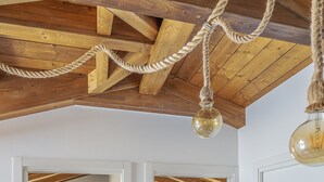 Una stanza con travi in legno, un lampadario in corda e due letti con testiere.