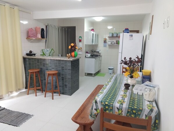 A compact kitchen with a dining area, featuring a small island, stools, and a table with a patterned tablecloth.