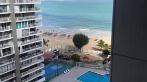 Un edificio alto con numerosi balconi affacciato su una spiaggia con piscina e lettini.