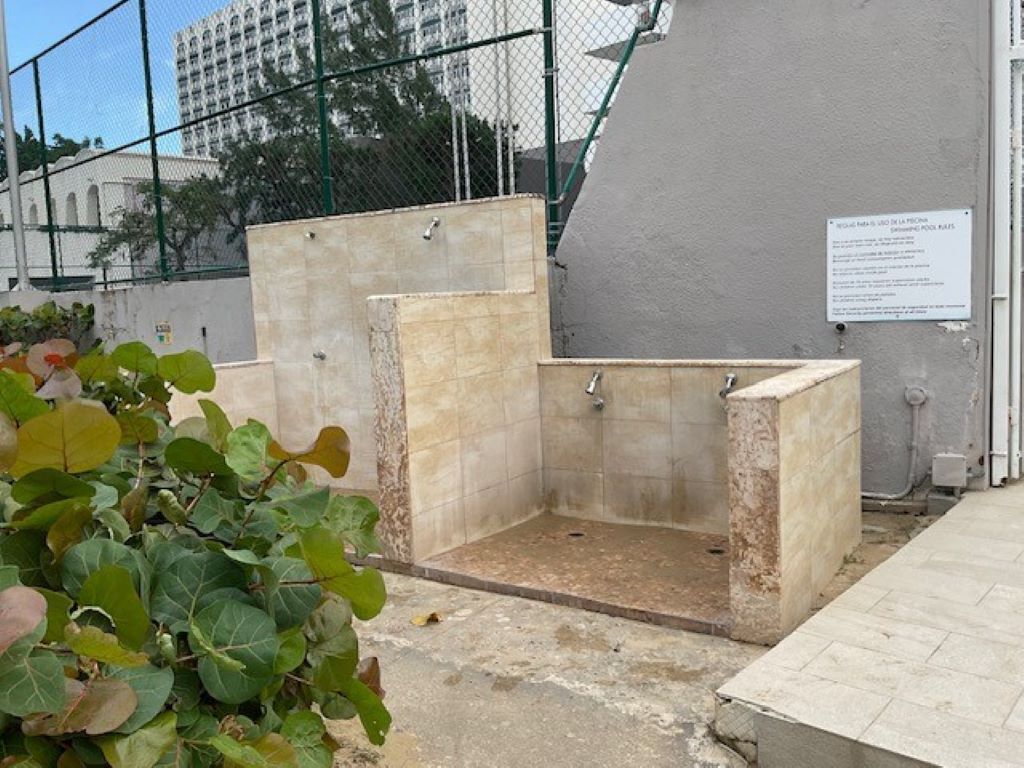 A small, enclosed shower area with tiled walls and floor, surrounded by a fence.