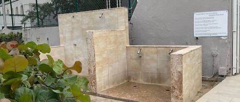 A small, enclosed shower area with tiled walls and floor, surrounded by a fence.