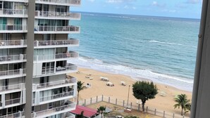 Un grattacielo con numerosi balconi affacciato su una spiaggia con sabbia e onde oceaniche.