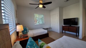 A hotel room with a bed, a TV, a ceiling fan, a window with blinds, and a small table. - "Gorgeous and Open" 2 Bedroom / 2 Bath Villa (Bimini)