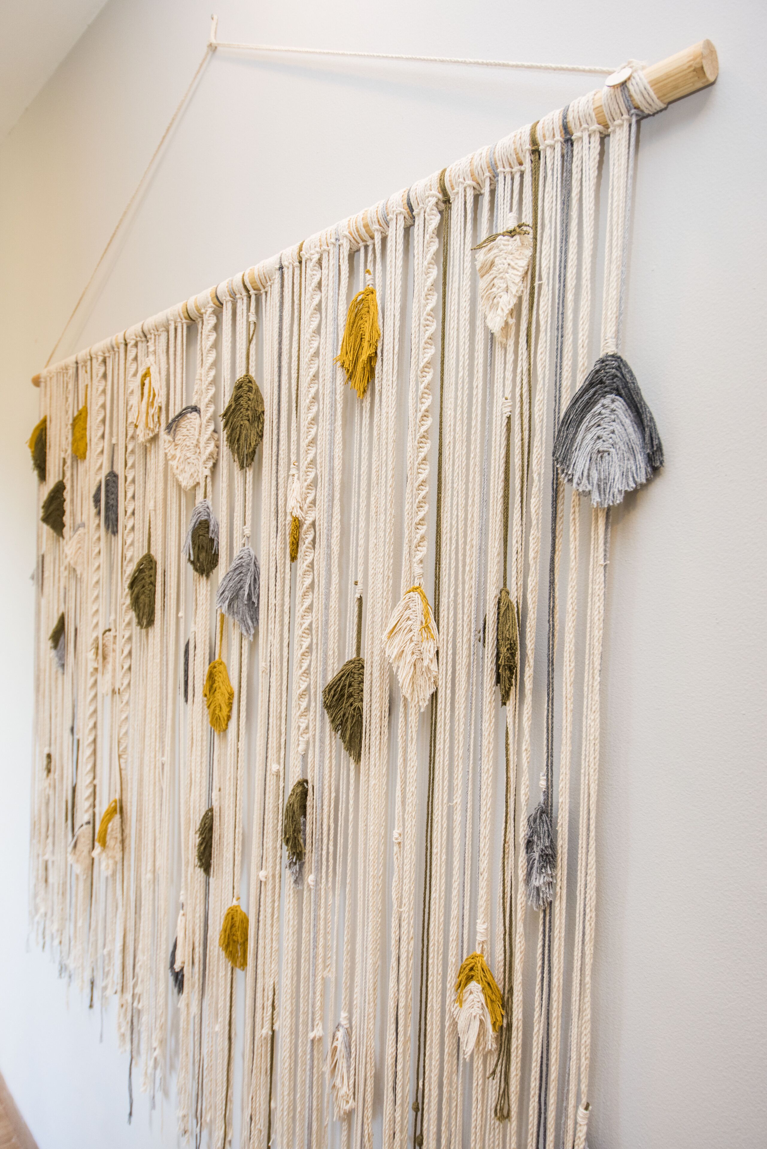 A macramé wall hanging with various colored tassels.