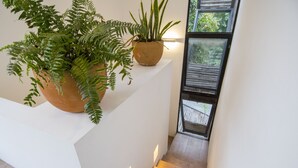 Eine Treppe mit weißer Wand und Holzstufen, die zu einem Balkon mit Blick auf Bäume führt.