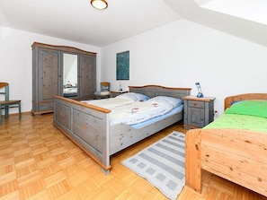 Een slaapkamer met een houten bed, een kledingkast, een spiegel, een nachtkastje en een nachttafeltje.