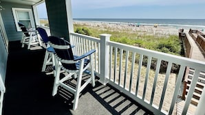 A covered porch with two Adirondack chairs and a view of the beach. - Cape Coddages I 103 2 Bedroom Condo by RedAwning (Surfside Beach)