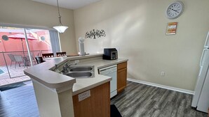 A modern kitchen with a central island, a built-in dishwasher, and a dining area with chairs and a table.