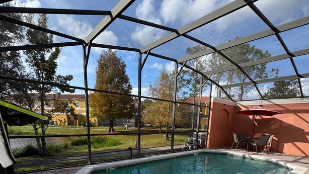 Piscina ao ar livre coberta com área de terraço, incluindo uma espreguiçadeira e uma mesa com guarda-sol.