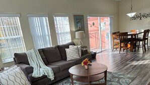 A living room with a sofa, a coffee table, and a dining area with chairs and a table.