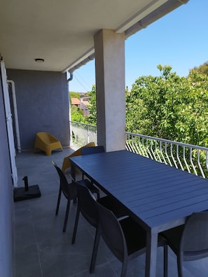 Un patio al aire libre con una mesa, sillas y un taburete amarillo, además de una barandilla de metal.