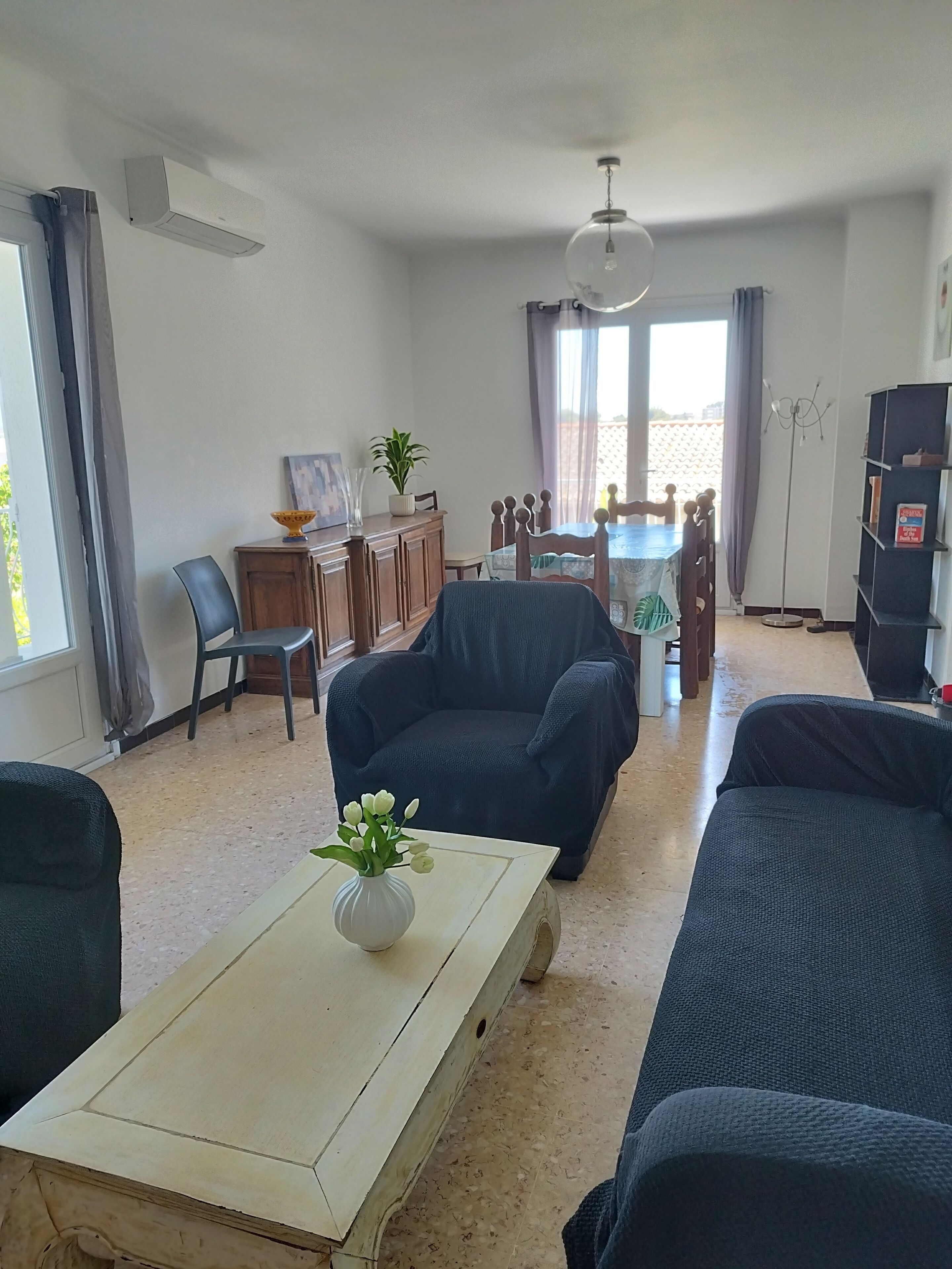 A living room with a sofa, a coffee table, and a dining area with chairs and a table.