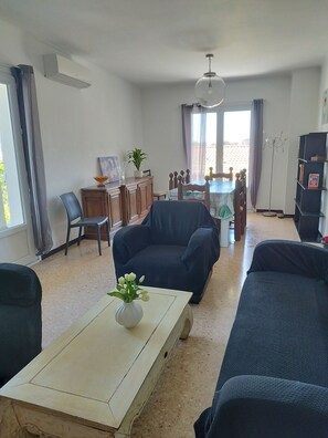 Un salon comprenant un canapé, une table basse et un coin repas avec des chaises et une table.