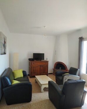 Een woonkamer met een bank, stoelen, een salontafel, een televisie en een open haard.