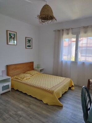 A bedroom with a wooden bed, a bedside table, a hanging light fixture, and two framed pictures on the wall. - 800m from beaches top of quiet villa, garden, balcony, parking and shops (Six-Fours-les-Plages)