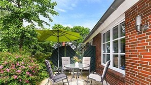 A patio with a table and chairs, a small toy car, and a green umbrella.