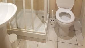Un baño con ducha de vidrio, inodoro y lavamanos.