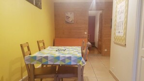 Un comedor con una mesa cubierta por un mantel de estampado geométrico, sillas de madera y una pared de madera.